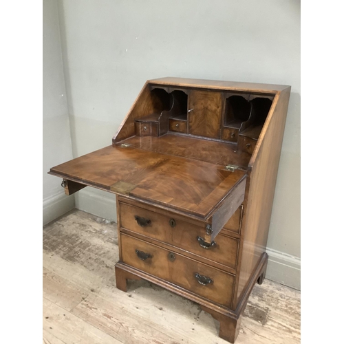 328 - A reproduction walnut bureau having a fall front with a fitted interior, above four graduated drawer... 