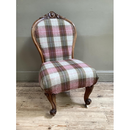 329 - A Victorian walnut nursing chair having an encircling frame with carved crest, on scroll feet, re-up... 