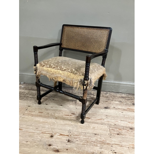 369 - An ebonised bobbin turned armchair having cane back on bobbin framing with with upholstered seat