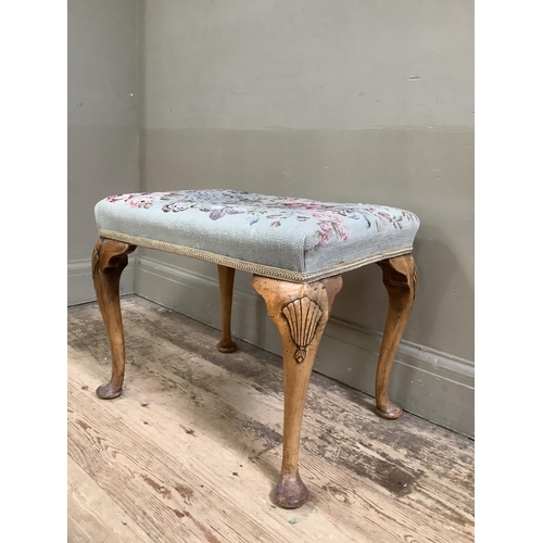 387 - A walnut dressing stool on cabriole legs with shell carvings to the shoulder with tapestry upholster... 