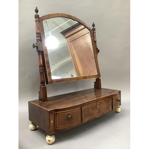 374 - An early 19th century mahogany crossbanded toilet mirror having brass finials above three drawers on... 