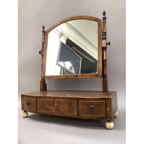 374 - An early 19th century mahogany crossbanded toilet mirror having brass finials above three drawers on... 