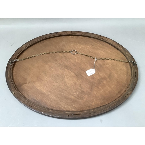 386 - An oak oval wall mirror with bevelled glass