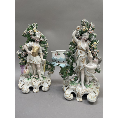 18 - A pair of 19th century Derby style candlesticks  modelled as Mars and Venus, both in front of bocage... 