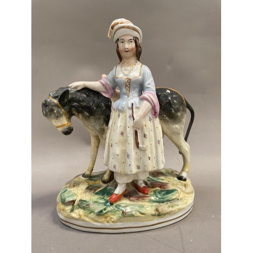 20 - A Staffordshire pottery figure of a girl with donkey on grassy mound, 25cm high