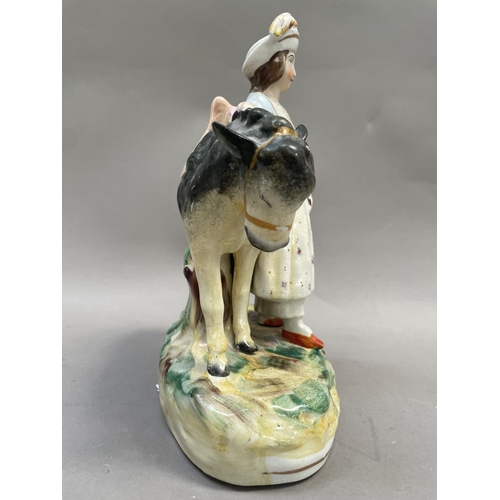 20 - A Staffordshire pottery figure of a girl with donkey on grassy mound, 25cm high