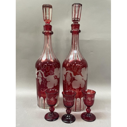 37 - A pair of ruby glass decanters with etched decoration of fruiting vine together with three matching ... 