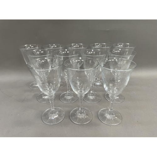 121 - A suite of twelve wine glasses having flared rims with etched bowls on knopped setms