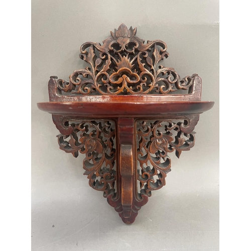 40 - A fruitwood wall shelf, the back and support heavily carved and pierced with foliate forms, having s... 