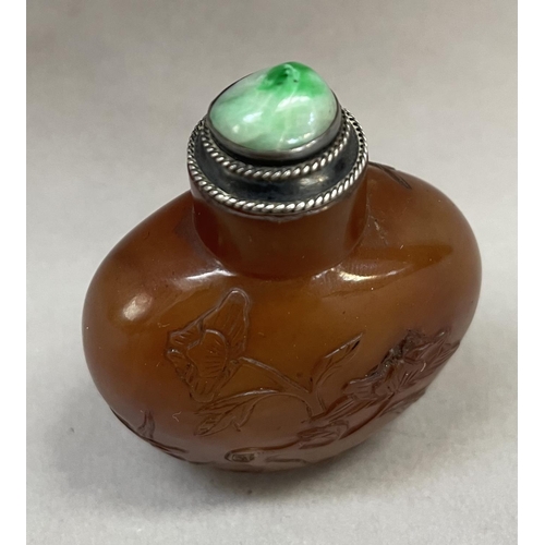 4 - A Chinese cornelian snuff bottle, carved with flowering prunus having a silver mounted stopper and s... 