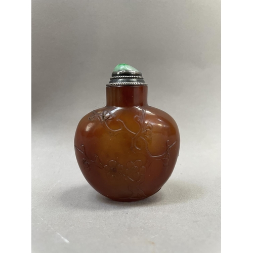 4 - A Chinese cornelian snuff bottle, carved with flowering prunus having a silver mounted stopper and s... 