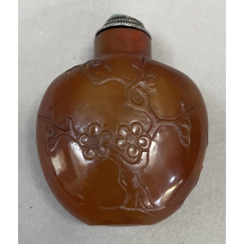 4 - A Chinese cornelian snuff bottle, carved with flowering prunus having a silver mounted stopper and s... 