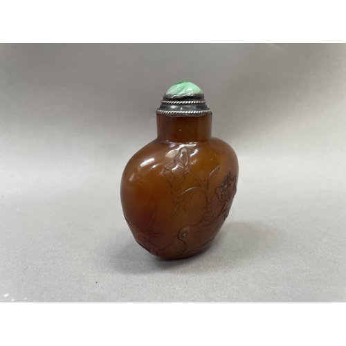 4 - A Chinese cornelian snuff bottle, carved with flowering prunus having a silver mounted stopper and s... 