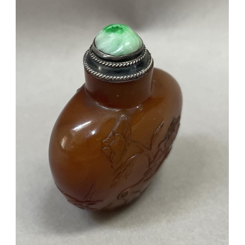 4 - A Chinese cornelian snuff bottle, carved with flowering prunus having a silver mounted stopper and s... 