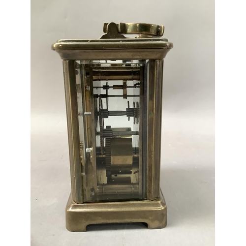 24 - A gilt brass carriage clock with enamel dial and black Roman numerals, visible escapement, 15cm high