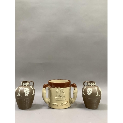 25 - A salt glaze loving cup with three handles formed as greyhounds together with two brown glazed jaspe... 