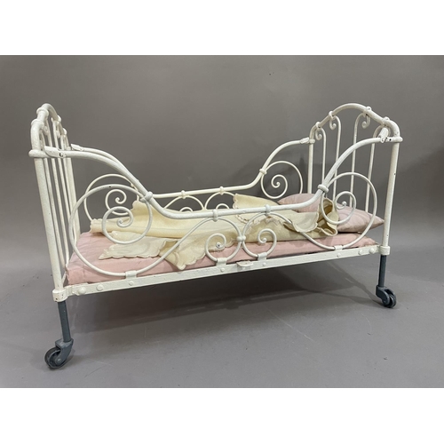 79 - A 19th century white painted iron doll's cot, having four wheels with filigree frame