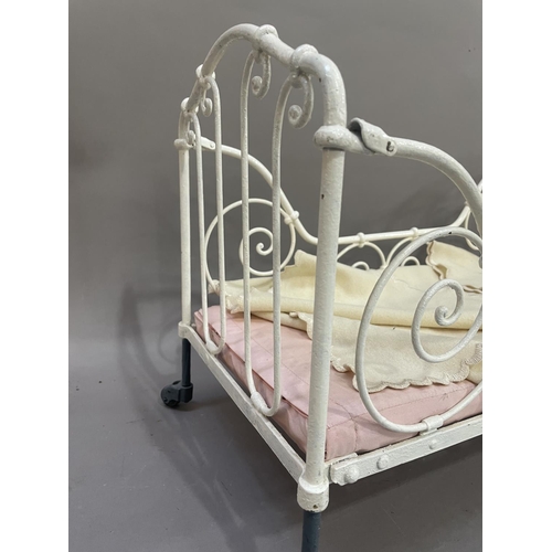 79 - A 19th century white painted iron doll's cot, having four wheels with filigree frame