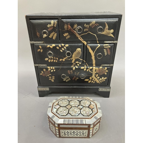 45 - An ebonised lacquered table top chest of drawers, metal bound having gilt painted decoration of bird... 