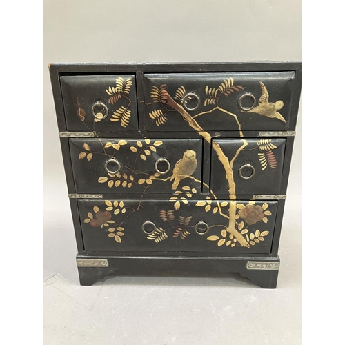 45 - An ebonised lacquered table top chest of drawers, metal bound having gilt painted decoration of bird... 