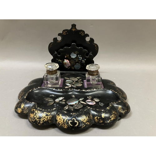 8 - A Victorian black lacquered inkstand, painted with gilt and inlaid with mother of pearl having two i... 