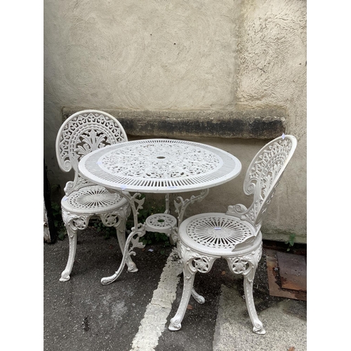 113 - A cast iron  white painted garden table with two high backed chairs