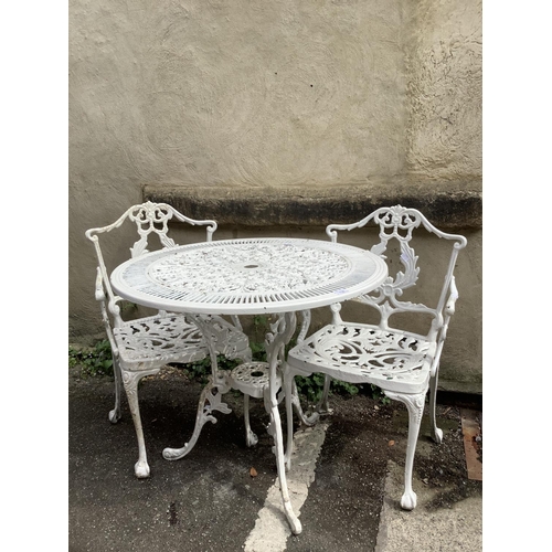 114 - A white painted cast iron garden table having two carver chairs