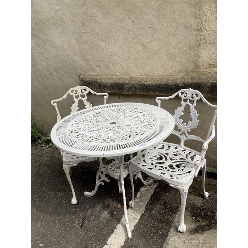 114 - A white painted cast iron garden table having two carver chairs