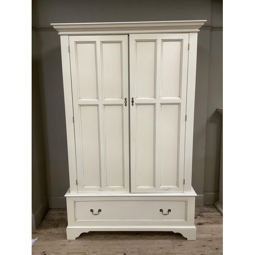 84 - A white, painted wardrobe with brass mounts, having double drawers above one drawer on bracket feet,... 