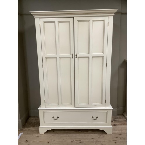 84 - A white, painted wardrobe with brass mounts, having double drawers above one drawer on bracket feet,... 