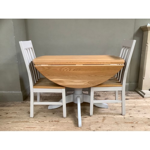 90 - A oak and grey painted circular dining table with two farmhouse chairs