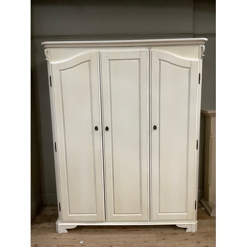 97 - A cream continental-style triple wardrobe having a straight top with moulded corners on bracket feet... 