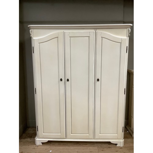 97 - A cream continental-style triple wardrobe having a straight top with moulded corners on bracket feet... 