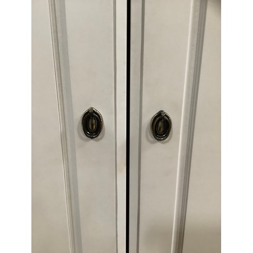 97 - A cream continental-style triple wardrobe having a straight top with moulded corners on bracket feet... 