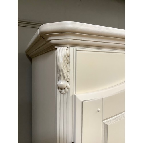 97 - A cream continental-style triple wardrobe having a straight top with moulded corners on bracket feet... 