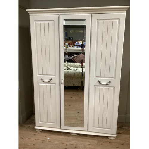 99 - A cream, mirrored triple wardrobe, the mirrored door surmounted by two panel doors with brushed chro... 