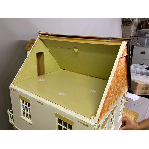 499 - A large dolls house on a wheeled plinth with opening front and rear, opening roof panels, a passenge... 