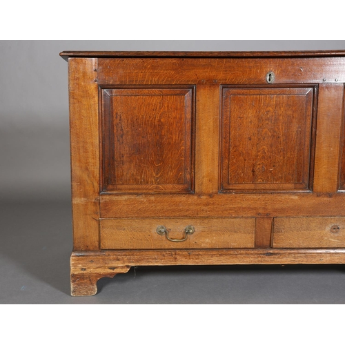 379 - AN 18TH CENTURY OAK MULE CHEST having a hinged top above a triple field panel front and two drawers,... 