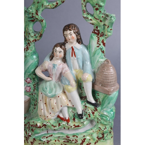 152 - A MID 19TH CENTURY STAFFORDSHIRE POTTERY FIGURE GROUP of a young man and girl sitting beneath a bowe... 