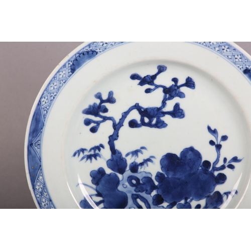 174 - AN 18TH CENTURY CHINESE BLUE AND WHITE PLATE painted with rocks issuing blossom within a diaper bord... 