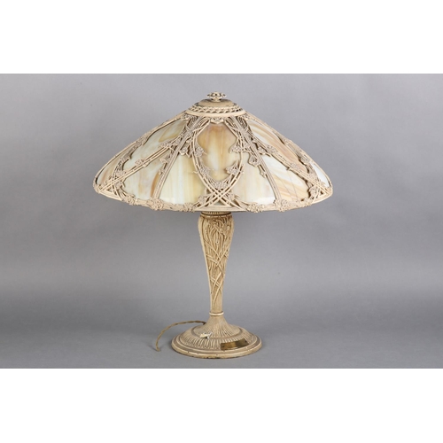 96 - A LATE ART NOUVEAU CAST METAL TABLE LAMP, the domed shade of slag glass overlaid with open panels of... 