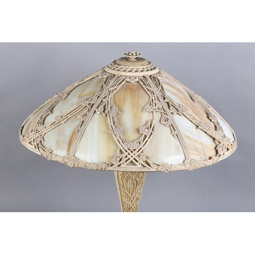 96 - A LATE ART NOUVEAU CAST METAL TABLE LAMP, the domed shade of slag glass overlaid with open panels of... 