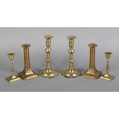 90 - A PAIR OF GEORGE III BRASS CANDLESTICKS with barrel-shaped nozzles, knopped stems on circular spread... 