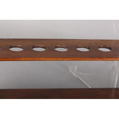 114 - A 19TH CENTURY MAHOGANY WALL RACK, the top having sixteen circular apertures above a lower shelf, 75... 