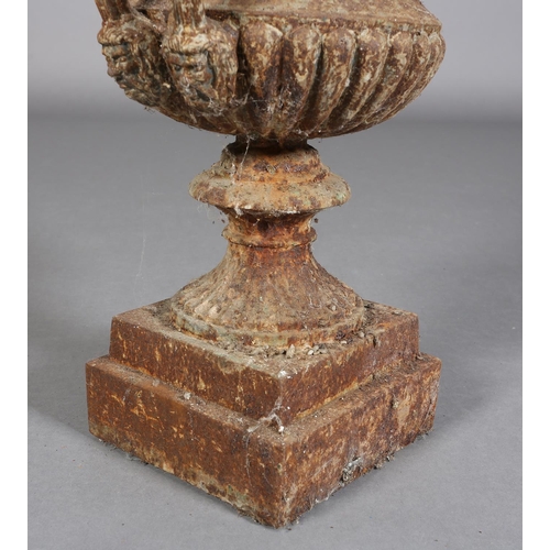 82 - A VICTORIAN CAST IRON GARDEN URN of two-handled campagna shape with band of scrolling flower and fol... 