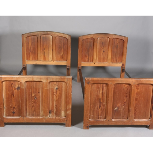 315 - A PAIR OF ARTS & CRAFTS PITCH PINE SINGLE BEDSTEADS, having arched and rectangular triple indented p... 