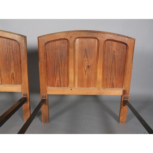 315 - A PAIR OF ARTS & CRAFTS PITCH PINE SINGLE BEDSTEADS, having arched and rectangular triple indented p... 