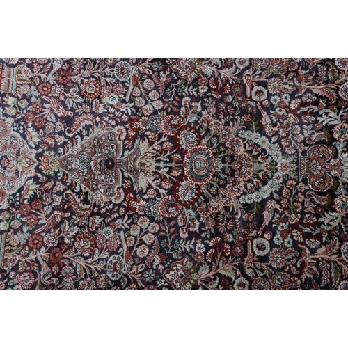 307 - A TABRIZ SILK CARPET, the dark blue field with urns of flowers flanked by flowering trees and birds,... 