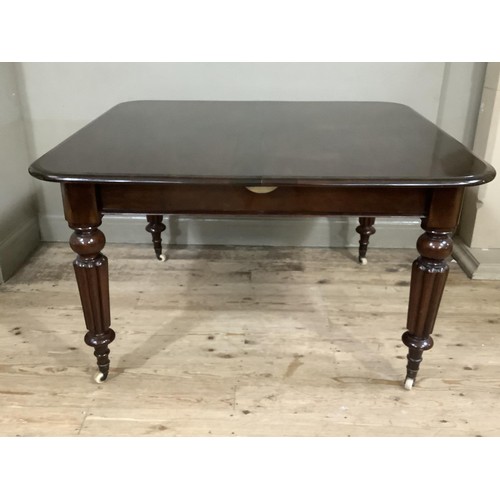 362 - A REPRODUCTION VICTORIAN MAHOGANY DINING TABLE on turned and reeded legs, brass caps and ceramic cas... 