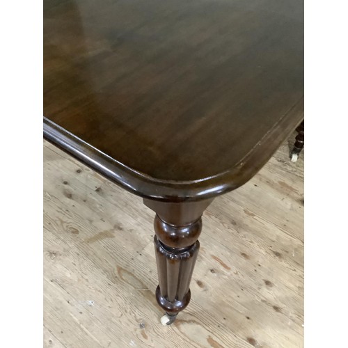 362 - A REPRODUCTION VICTORIAN MAHOGANY DINING TABLE on turned and reeded legs, brass caps and ceramic cas... 